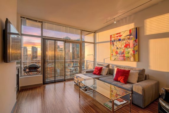 Seattle Condo - 2018 Modern living room with large windows, city views, and colorful artwork on the wall.