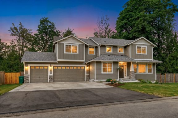 2019 Modern two-story gray house with a double garage, landscaped yard, and evening sky.