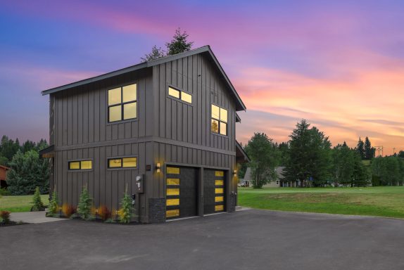 Modern two-story building with large windows and a colorful sunset sky behind it.