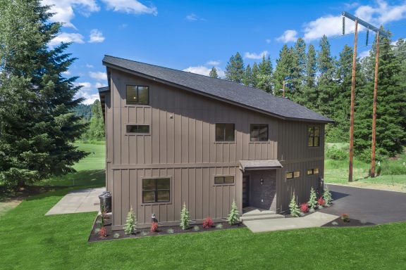 Modern two-story home with a sloped roof, surrounded by grass and trees.
